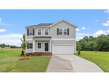 Charming two-story home with gray siding, an attached garage, and a well-manicured lawn at 89 Grove Township Way, Angier, NC 27501