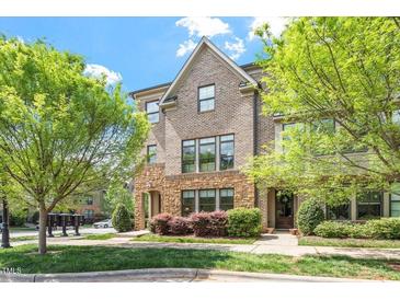Inviting brick townhouse featuring manicured landscaping, stone accents, and mature trees at 1601 Bowery Dr, Raleigh, NC 27607
