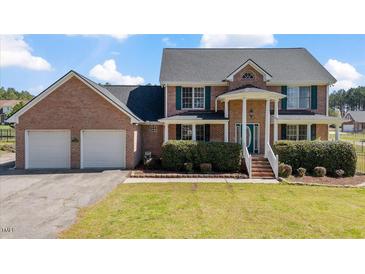 Charming two-story brick home featuring an attached two-car garage and a well-manicured front yard at 80 Greta Ln, Henderson, NC 27537