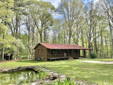 Charming brick home with a covered porch, red metal roof and a lovely pond at 1622 N Carolina 98 Hwy W, Louisburg, NC 27549