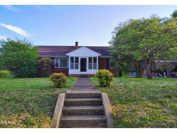 Charming brick home featuring a quaint front porch and well-maintained landscaping at 919 E Main St, Haw River, NC 27258
