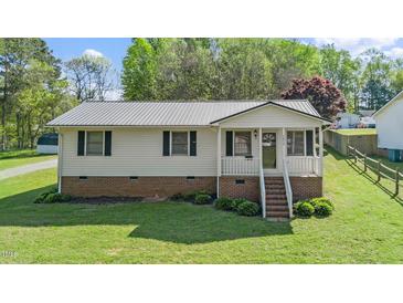 Charming single-story home with brick foundation, metal roof, and a well-manicured lawn at 1017 S Second Ave, Siler City, NC 27344