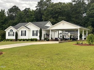 Traditional home featuring white siding, black shutters, a covered carport, and a well-manicured lawn at 132 Crystal Pl, Benson, NC 27504
