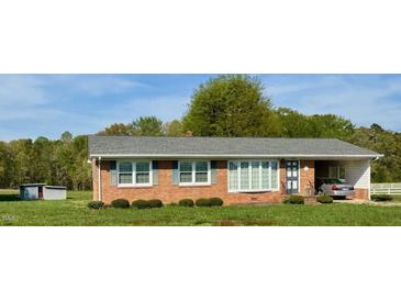 Charming brick ranch home with manicured lawn and attached carport providing functional curb appeal at 1829 Stewart Farm Rd, Henderson, NC 27537