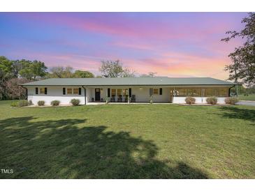 Charming single-story home with a brick facade, spacious front yard and rocking chairs on a covered porch at 2960 Epps Clark Rd, Siler City, NC 27344