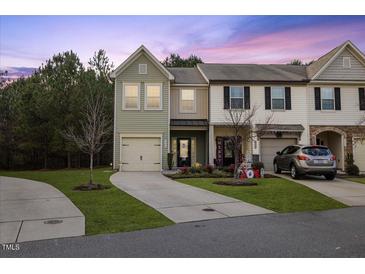 Charming townhome featuring a two-car garage, well-maintained lawn, and welcoming curb appeal at dusk at 3735 Landshire View Ln, Raleigh, NC 27616