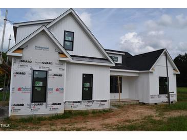 Modern farmhouse exterior featuring white siding, black trim, and a gabled roof under construction at 4330 Medicus Ln, Franklinton, NC 27525