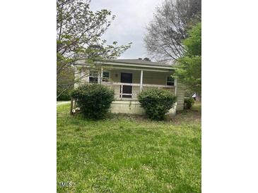 Charming single-story home with a cozy front porch surrounded by lush greenery and mature trees at 108 Virgil Rd, Durham, NC 27703