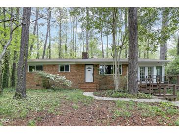 Charming brick ranch-style home with a landscaped front yard and inviting entryway surrounded by mature trees at 208 Clark Lake Rd, Durham, NC 27707
