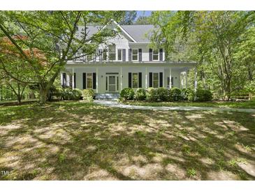 Charming two-story home featuring a welcoming front porch surrounded by mature trees and lush landscaping at 216 Dairyland Rd, Chapel Hill, NC 27516