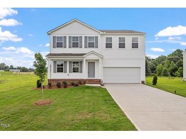 Charming two-story home with a well-manicured lawn, attached two-car garage, and classic architectural details at 59 Grove Township Way, Angier, NC 27501