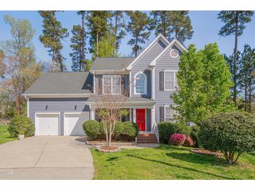 Charming two-story home with a vibrant red door, well-manicured lawn and an attached two-car garage at 709 Basil Dr, Durham, NC 27713