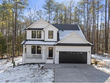 Charming two-story home with a black garage door, inviting front porch and landscaped yard at 7218 Sunrise Rd, Chapel Hill, NC 27514
