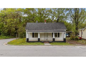 Charming single-story home featuring a covered front porch, black accents, and mature trees at 905 David St, Henderson, NC 27536