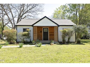 Charming home with white siding, a modern black front door, and a well-manicured lawn at 1015 Washington St, Burlington, NC 27217
