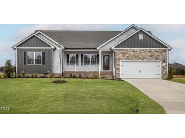 Charming home featuring stone accents, a covered porch, and a well-manicured lawn at 11740 International Dr, Middlesex, NC 27557