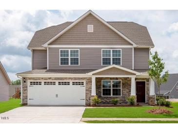 Two-story home features stone accents, attached two-car garage, and well-maintained landscaping at 302 Shiloh Way, Mebane, NC 27302