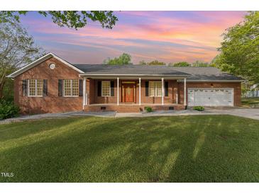 Charming brick home with a covered front porch, black shutters, and a well-maintained lawn and garage at 317 William Dr, Benson, NC 27504