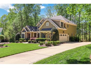 Traditional two-story home with attached garage and driveway surrounded by mature trees and manicured landscaping at 572 W Walker Woods Ln, Clayton, NC 27527