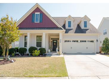 Charming home with a two-car garage, dormer windows, landscaped yard, and a welcoming front porch at 828 Traditions Ridge Dr, Wake Forest, NC 27587