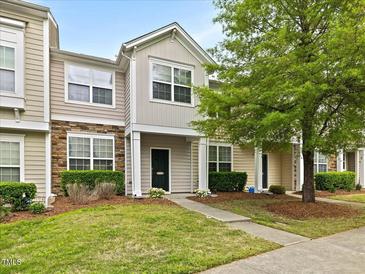 Inviting townhome featuring stone accents, neutral siding, manicured lawn, and walkway leading to the front door at 1605 Grace Point Rd, Morrisville, NC 27560