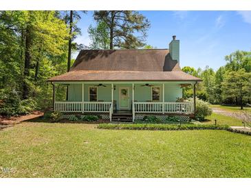 Charming home with a covered front porch, manicured lawn, and lush greenery at 209 Pen Lou Ct, Angier, NC 27501