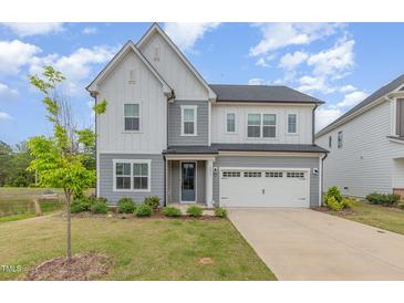 Charming two-story home with a well-manicured lawn and a two-car garage on a sunny day at 2434 Heron Watch Pl, Fuquay Varina, NC 27526