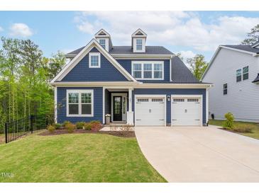 Charming two-story home with a blue exterior, white trim, dormer windows, and a two-car garage at 261 Emory Bluffs Dr, Holly Springs, NC 27540