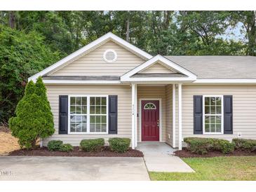 Charming home featuring beige siding, black shutters, landscaped yard, and a striking maroon front door at 411 A Aversboro Rd, Garner, NC 27529
