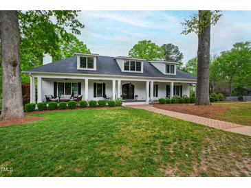 Inviting white brick home with a covered front porch and manicured lawn, creating a warm and welcoming curb appeal at 4237 Rowan St, Raleigh, NC 27609