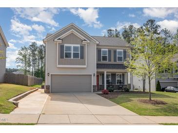 Two-story home with gray siding, brick accents, an attached two-car garage, and a manicured front lawn at 528 Holden Forest Dr, Youngsville, NC 27596