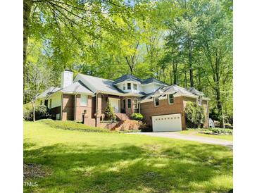 Beautiful brick home with mature trees, a front lawn, and a two-car garage at 6212 Trevor Ct, Raleigh, NC 27613