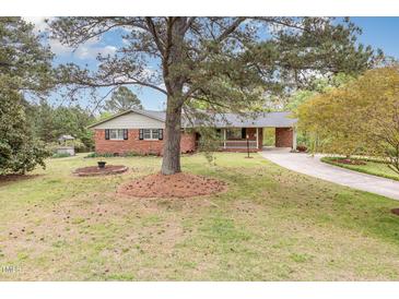 Charming brick home with a spacious front yard, mature trees, and a welcoming driveway at 1750 Spring Valley Lake Rd, Henderson, NC 27537