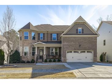 Charming two-story brick home featuring a two-car garage, covered entry, and manicured landscaping at 1911 Firenza Dr, Apex, NC 27502