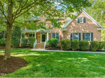 Charming brick home with a well-manicured lawn, lush greenery, and a welcoming front porch at 314 Hogan Woods Cir, Chapel Hill, NC 27516