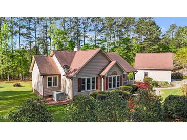 Charming tan home featuring a brick chimney, mature landscaping, and an accessory building at 50 Gill Ln, Fuquay Varina, NC 27526