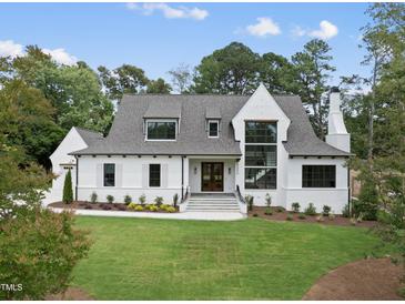 Elegant home showcasing a manicured lawn, classic white siding, and a welcoming entrance at 5504 Kingwood Dr, Raleigh, NC 27609