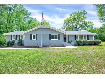 Charming single-story home featuring a well-manicured lawn, a gray brick facade and inviting curb appeal at 612 E Academy St, Fuquay Varina, NC 27526