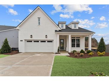 Charming white brick home featuring a two-car garage, well-maintained landscaping, and a welcoming front porch at 616 Gainer Dr # 15, Raleigh, NC 27610