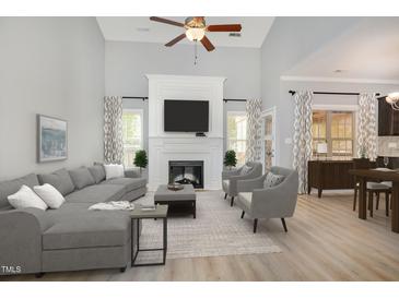Bright living room with fireplace, large sectional sofa, accent chairs, and hardwood floors at 8021 Crookneck Dr, Angier, NC 27501