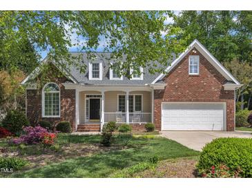 Charming brick home featuring a welcoming front porch, attached garage, and lush landscaping at 103 Temple Gate Dr, Cary, NC 27518