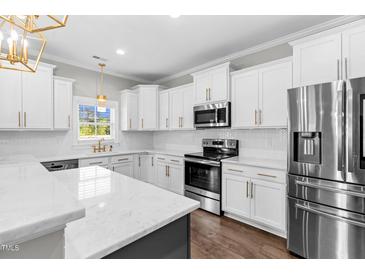 Bright kitchen features white cabinetry, stainless steel appliances, granite countertops, and hardwood flooring at 105 Blooms Way, Kenly, NC 27542
