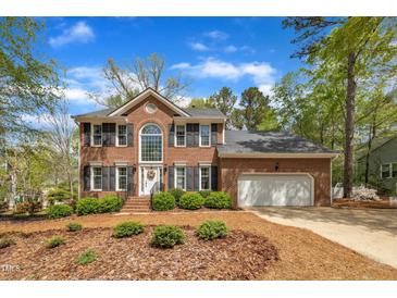 Brick two-story home featuring a well-manicured front yard, black shutters, and an attached two-car garage at 1100 Queensbury Cir, Durham, NC 27713