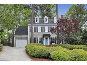 Charming two-story home with a light gray exterior, blue door, dormer windows, and lush landscaping at 117 Vicksburg Dr, Cary, NC 27513