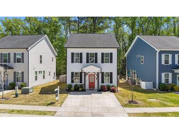 Charming two-story home with white siding, black shutters, a red front door, and a well-manicured front lawn at 166 Yellow Jacket Rdg, Clayton, NC 27520