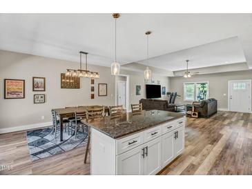 Open-concept living room with kitchen island, dining area, and modern décor, perfect for entertaining guests at 1730 Willie Pace Rd, Burlington, NC 27217