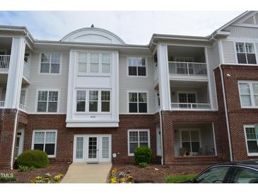 Three-story condo building with brick facade and multiple balconies, complemented by vibrant landscaping at 224 Eyam Hall Ln, Apex, NC 27502