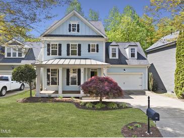 Charming two-story home featuring a covered front porch, well-manicured lawn, and attached two-car garage at 301 Marsh Landing Dr, Holly Springs, NC 27540