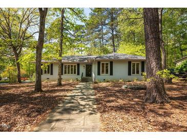 Charming single-story home with a stone walkway and surrounded by mature trees in a peaceful setting at 416 Colony Woods Dr, Chapel Hill, NC 27517