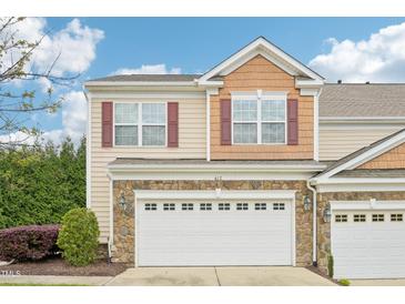 Charming townhome featuring a stone facade and two-car garage under a bright blue sky at 617 Sealine Dr, Cary, NC 27519